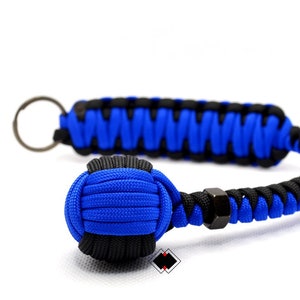 May include: A blue and black paracord keychain with a knotted ball at the end. The keychain has a metal ring for attaching keys.