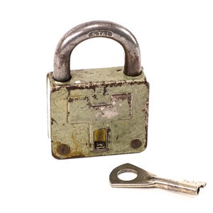 Peut inclure: Un cadenas ancien et usé avec une anse argentée et une clé assortie. Le corps du cadenas est vert olive délavé, avec des signes d'usure, suggérant l'âge et l'utilisation. La clé est posée à côté du cadenas sur fond blanc.