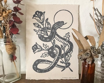Linograbado de serpientes y amapolas sobre papel hecho a mano, impresión tirada a mano, tinta dorada sobre papel negro, impresión de edición limitada