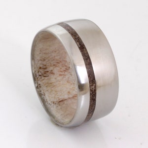 May include: A silver ring with a brown wood inlay. The ring is wide and has a rounded profile.