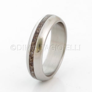 May include: A silver wedding band with a brown inlay. The band is smooth and polished.