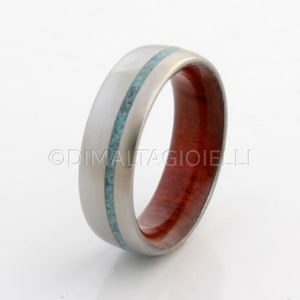 May include: A silver ring with a turquoise inlay and a red wood band.