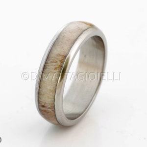 May include: A silver ring with a white antler inlay. The ring is polished and has a smooth finish.
