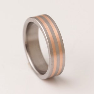 May include: A silver ring with two thin gold bands around the center.
