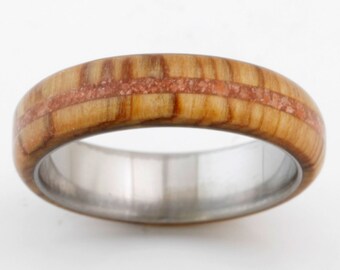May include: A wooden ring with a thin band of red wood inlay. The ring is made of natural wood and has a polished finish.