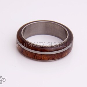 May include: A brown wooden ring with two white stripes around the band. The ring is made of wood and metal.