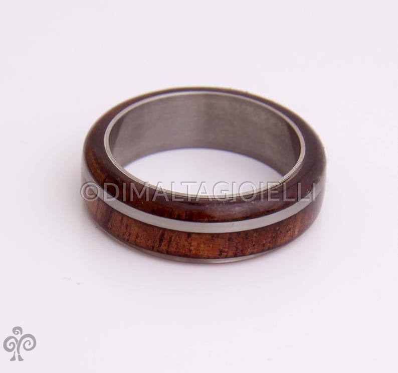 May include: A brown wooden ring with two white stripes around the band. The ring is made of wood and metal.