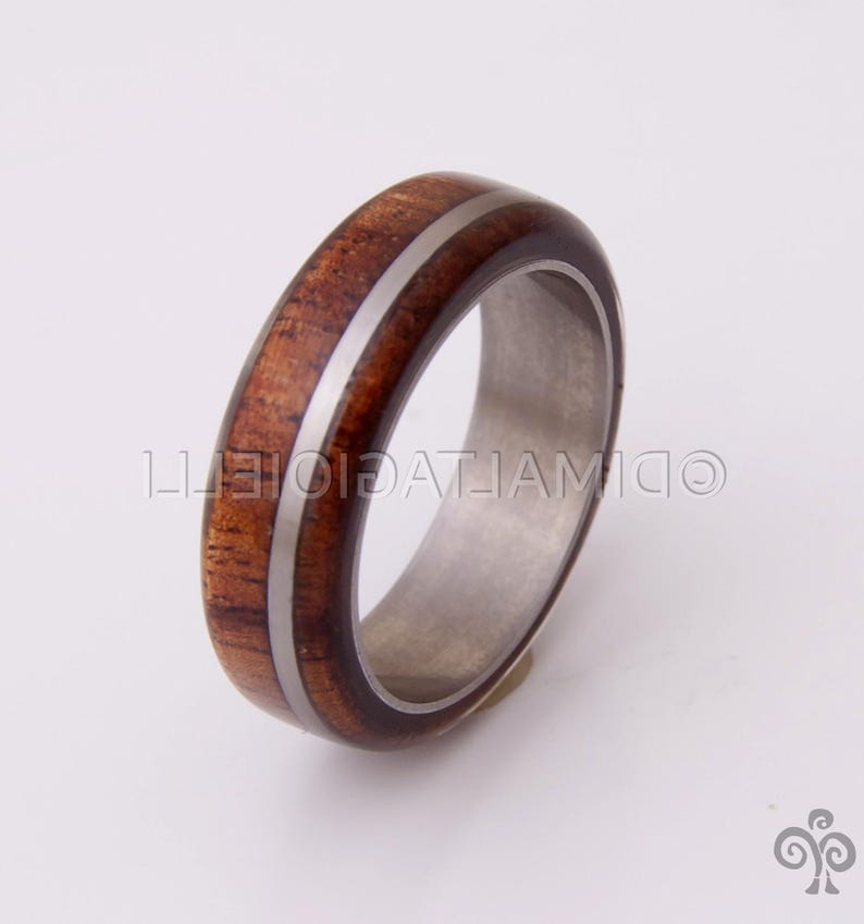 May include: A brown wooden ring with a silver inlay, set in a silver band.