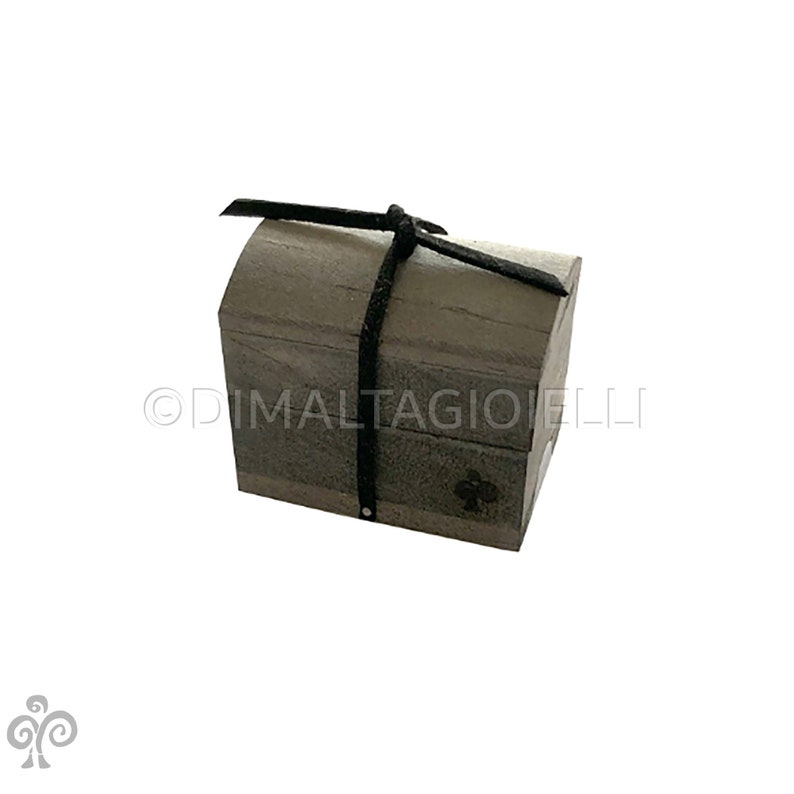 May include: A small wooden chest with a black leather strap tied around it. The chest is closed and has a slightly rounded top.