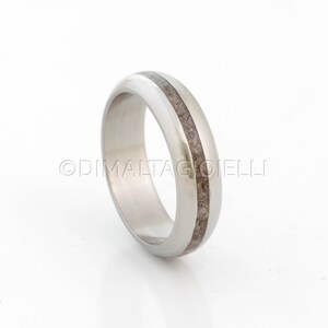 May include: A silver ring with a thin brown inlay. The ring is smooth and polished.