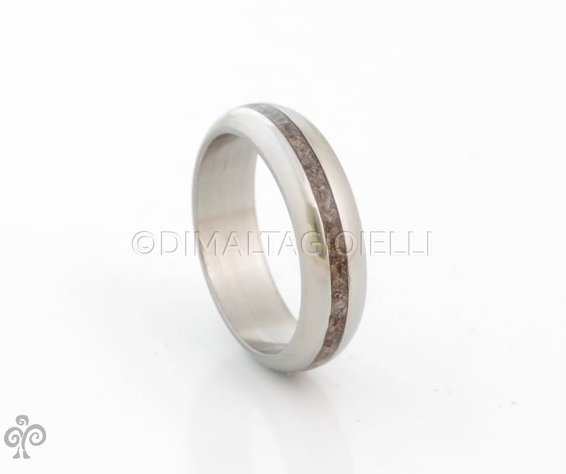 May include: A silver ring with a thin brown inlay. The ring is smooth and polished.