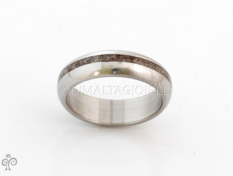 May include: A silver wedding band with a thin brown inlay.
