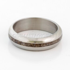 May include: A silver ring with a thin band of brown wood inlay.