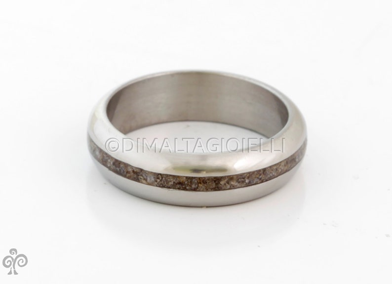 May include: A silver ring with a thin band of brown wood inlay.