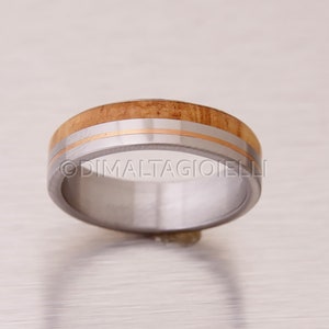 May include: A silver ring with a band of wood and two thin gold bands.
