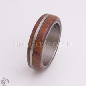 May include: A brown wooden ring with a silver inlay. The ring is made of wood and metal.