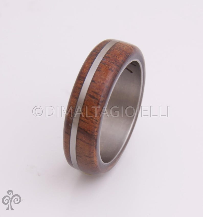May include: A brown wooden ring with a silver inlay. The ring is made of wood and metal.