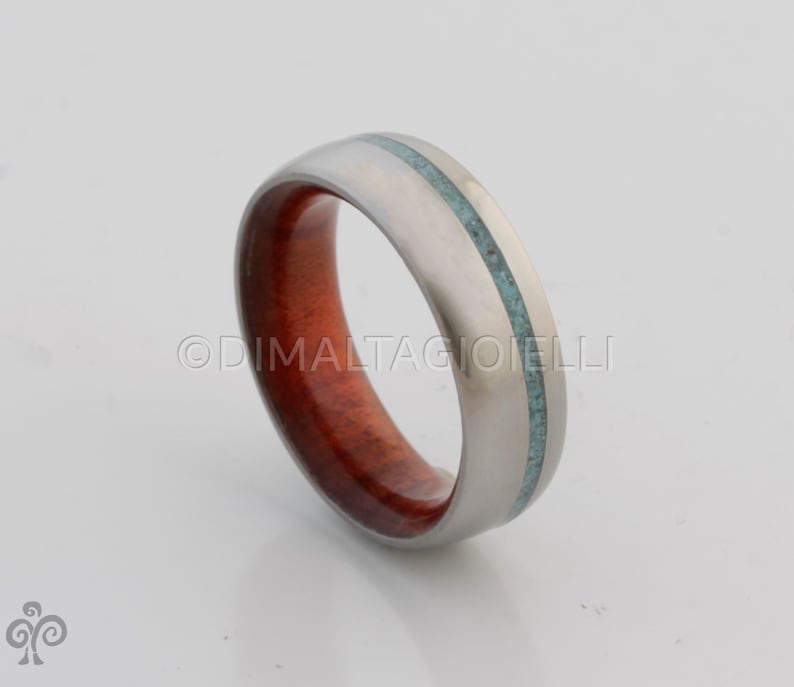May include: A silver titanium ring with a red wood inlay and a turquoise inlay.