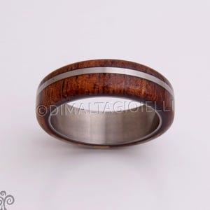 May include: A brown wooden ring with a silver inlay, set in a titanium band.