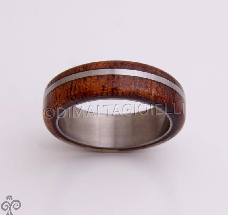 May include: A brown wooden ring with a silver inlay, set in a titanium band.