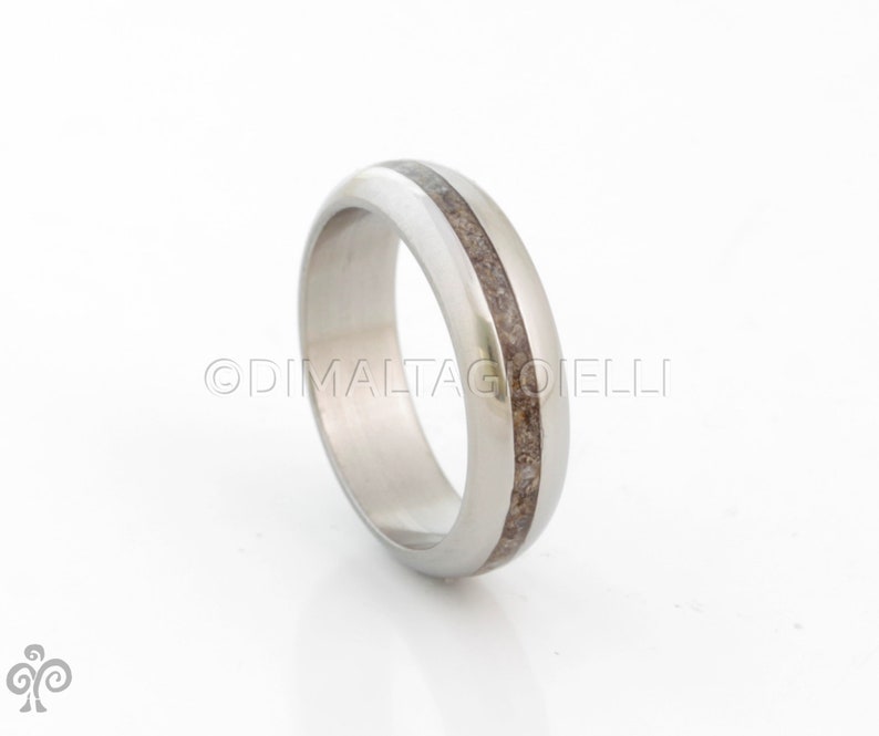 May include: A silver ring with a thin brown inlay. The ring is smooth and polished.
