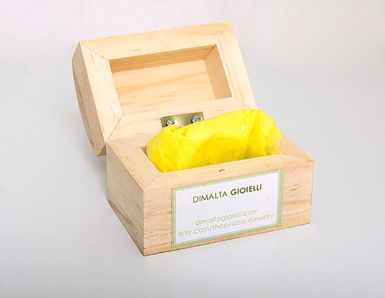 May include: A wooden box with a yellow tissue paper inside. The box has a label that says "DIMALTA GIOIELLI" and includes the website address "dimaltagioielli.com" and "etsy.com/shop/aboutjewelry".