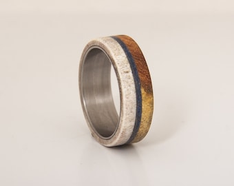May include: A ring made of white antler, brown wood, and a thin blue line. The ring is made of metal and has a polished finish.