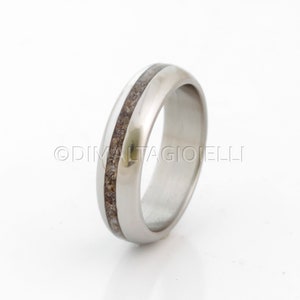 May include: A silver wedding band with a thin brown inlay.