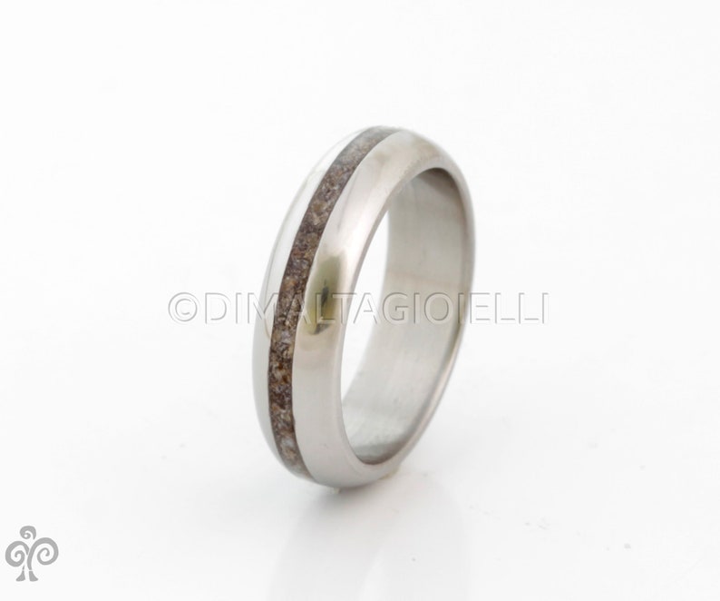 May include: A silver wedding band with a thin brown inlay.