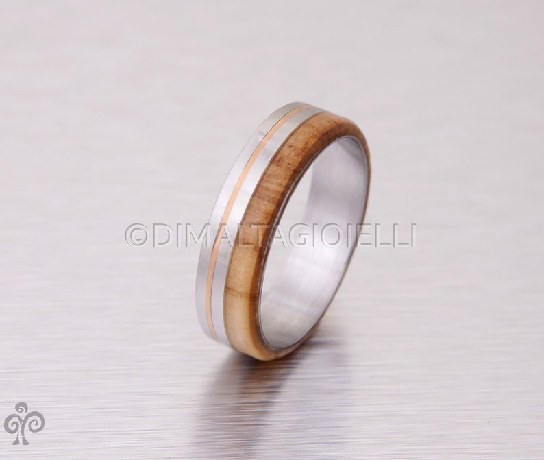 May include: A silver ring with a band of wood and a thin gold band around the wood.