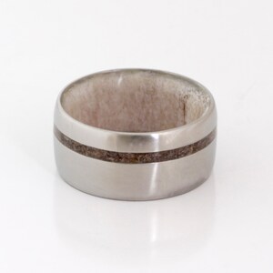 May include: A silver titanium ring with a brown wood inlay band.