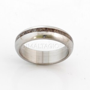 May include: A silver wedding band with a thin brown inlay.