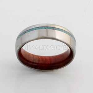 May include: A silver ring with a turquoise inlay and a red wood band.