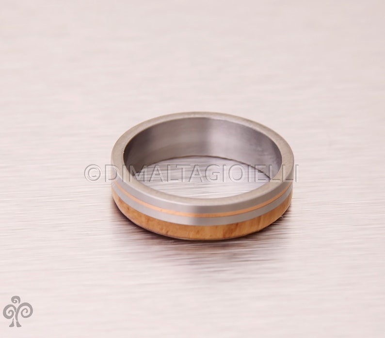 May include: A silver ring with a thin band of wood and a thin band of gold.