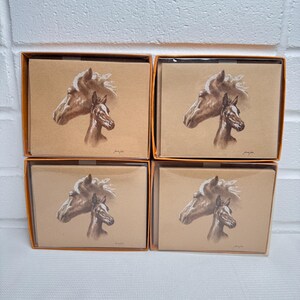 Puede incluir: Cuatro cajas de papelería con una ilustración detallada de un caballo y un potro en tonos marrones. La obra de arte está impresa en cartulina marrón claro, y las cajas tienen un borde naranja.