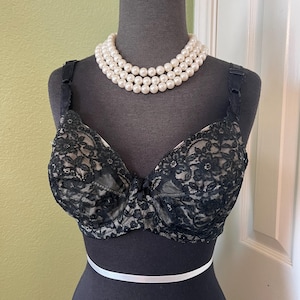May include: Black lace bra with a delicate floral pattern. The bra has adjustable straps and a hook and eye closure in the back.