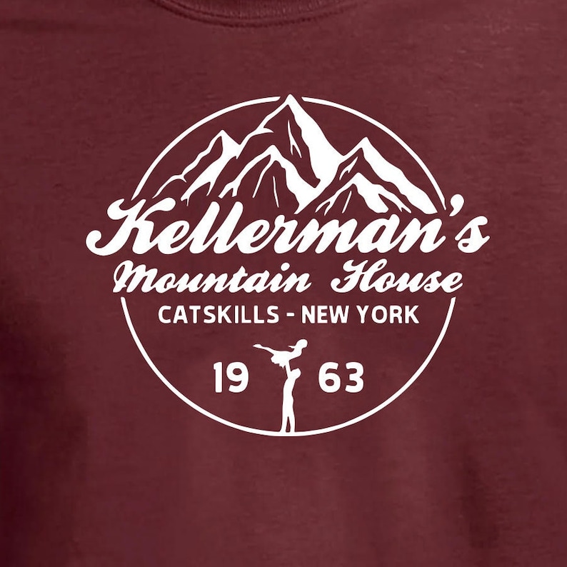 Puede incluir: Texto blanco sobre fondo marr&oacute;n que dice "Kellerman's Mountain House, Catskills - New York, 1963". Una imagen estilizada de monta&ntilde;as est&aacute; detr&aacute;s del texto. Una silueta de una pareja bailando est&aacute; debajo del texto.