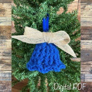 May include: A blue crocheted bell Christmas tree ornament with a burlap bow. The ornament is suspended by a blue ribbon. The text "Digital PDF" is visible at the bottom, against a backdrop of fir.