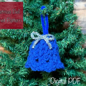 May include: A blue crocheted Christmas bell decoration with a silver bow and a blue loop for hanging. The ornament is displayed on a Christmas tree. Text on the image reads "Christmas Bell Crochet Pattern" and "Digital PDF".