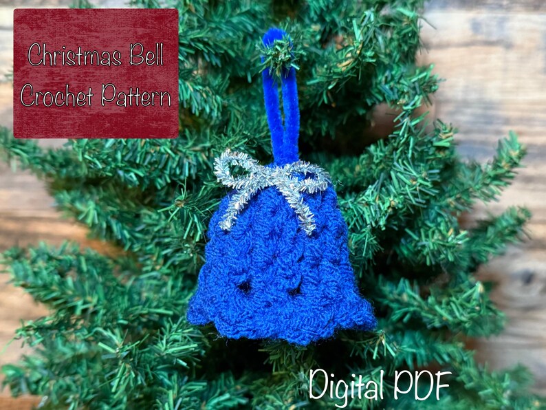 May include: A blue crocheted Christmas bell decoration with a silver bow and a blue loop for hanging. The ornament is displayed on a Christmas tree. Text on the image reads "Christmas Bell Crochet Pattern" and "Digital PDF".