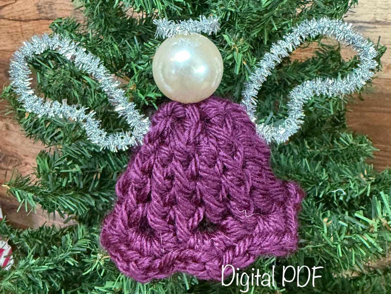 May include: A handmade Christmas angel decoration with a pearl-like head and a crocheted purple body. Silver tinsel forms the wings and halo. The words "Digital PDF" are at the bottom.