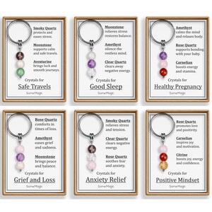 May include: Six keychains with crystal beads in various colors, each on a card with text. The keychains are labeled for Safe Travels, Good Sleep, Healthy Pregnancy, Grief and Loss, Anxiety Relief, and Positive Mindset.