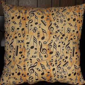 May include: A tan throw pillow with a black and white musical note pattern. The notes include treble clefs, eighth notes, quarter notes, and half notes.