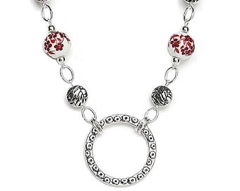 May include: A silver necklace with a circle pendant and red and white floral beads.
