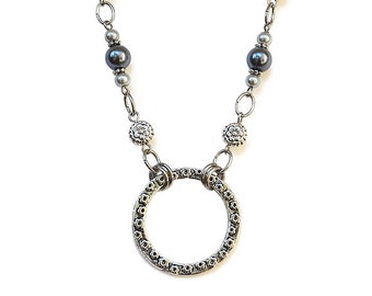 May include: A silver necklace with a circle pendant and gray beads. The circle pendant has a textured design.