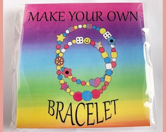 May include: A colorful rainbow background with the text "MAKE YOUR OWN BRACELET" in black. The image shows two colorful bracelets with various charms, including stars, hearts, flowers, and dice.