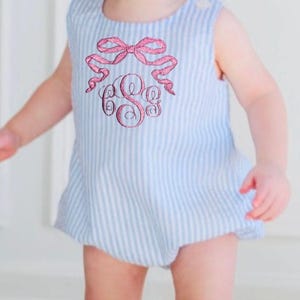 May include: A blue and white striped baby onesie with a pink bow and monogrammed with the letters "C S C".