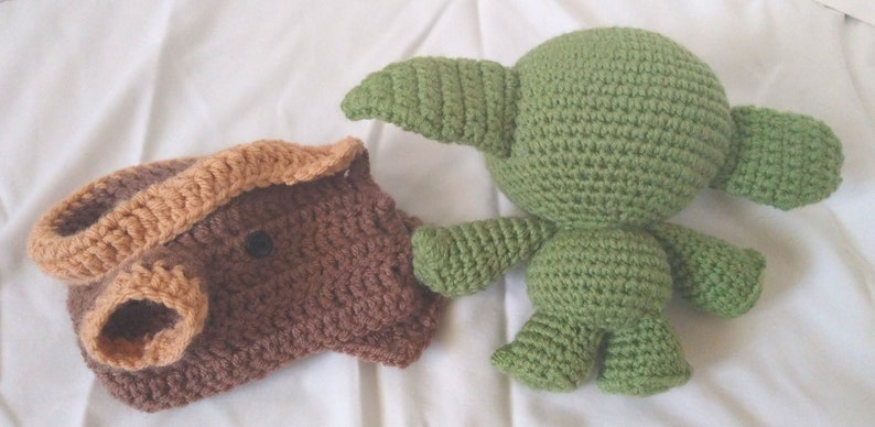 Pu&ograve; includere: Due giocattoli di peluche all'uncinetto. Uno &egrave; marrone con la faccia color beige e l'altro &egrave; verde con grandi orecchie.