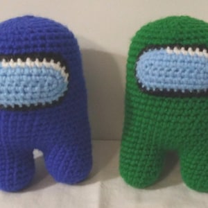 May include: Two crocheted plush toys shaped like characters from the video game Among Us. One is blue with a light blue visor and the other is green with a light blue visor.