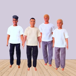 以下が含まれることがあります： カジュアルな服装の男性ファッション人形が4体。各人形は半袖シャツとズボンを着用しています。シャツは白とクリーム色で、ズボンは黒、グレー、紫です。人形は木の床の上に立っています。